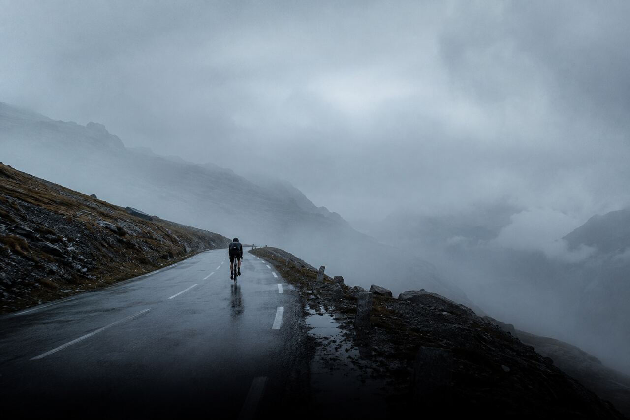 Solo cyclist on an empty mountain road in morning mist